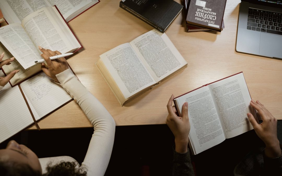 People studying multilingual reference books and language materials at a desk, representing professional translation and localization services.