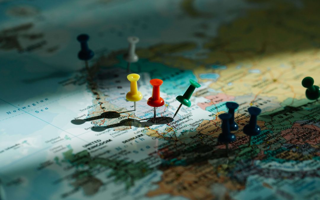 A close-up of a world map with colored push pins marking various locations in Europe, illuminated by natural light—highlighting the significance of translation and localization when connecting people across different regions.