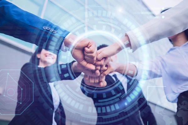 Several professionals join their fists together in a team gesture, overlaid with futuristic digital interface graphics representing collaboration, technology, and business connectivity.