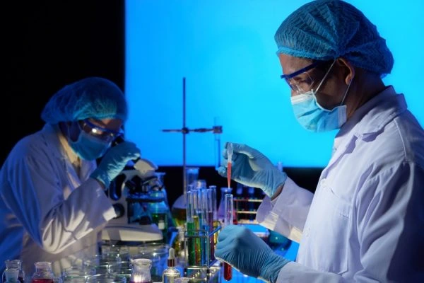 Laboratory professionals conducting clinical research and sample analysis using scientific equipment and test tubes in a modern laboratory.