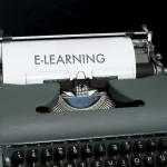 Vintage typewriter displaying the word “E-LEARNING” on paper, representing online language learning, digital education, and remote training.