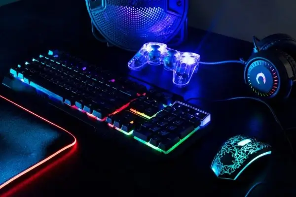Gaming setup with illuminated keyboard, mouse, controller, and headphones