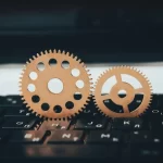 Two metallic gears positioned on a computer keyboard, symbolizing software localization workflows, translation technology, automation, and multilingual application development.