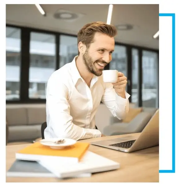 Professional workspace with person working on laptop and drinking coffee