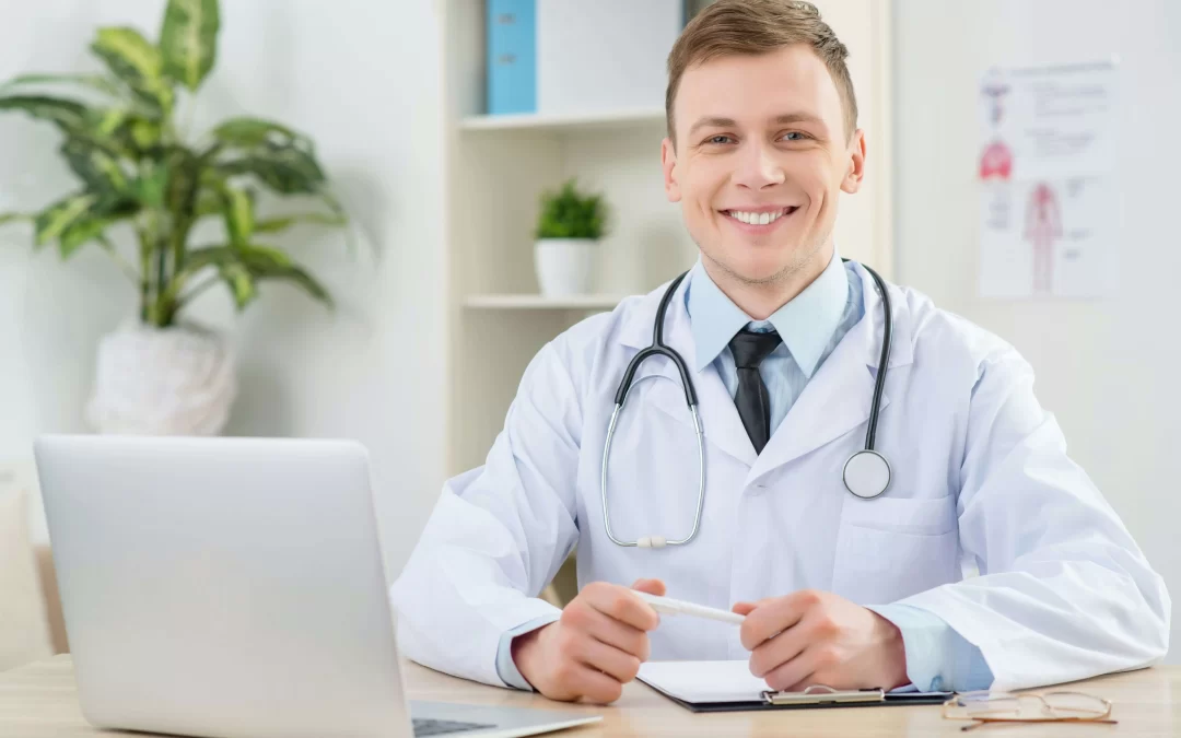 Professional doctor in white coat working at desk with laptop and medical documents