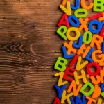 Colorful alphabet letters scattered on a wooden surface, representing multilingual communication, language translation, and software localization for global audiences.