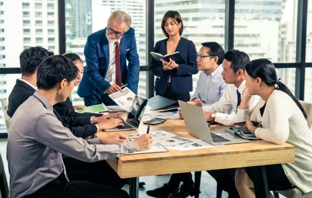 Business professionals collaborating around a conference table with laptops and documents, representing software localization strategy, multilingual product adaptation, and global market expansion.