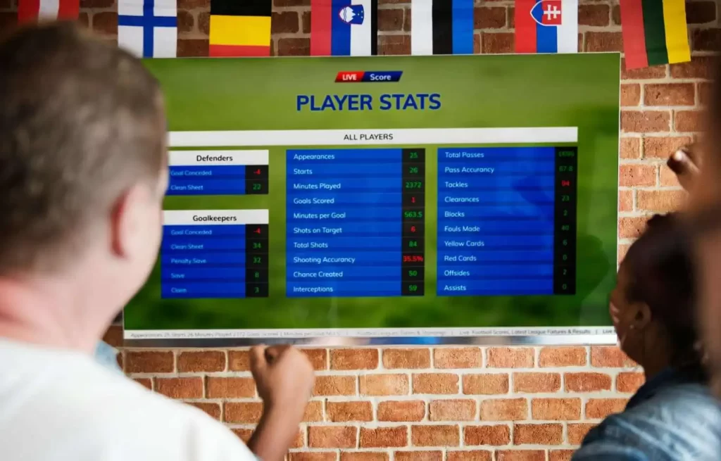 Sports fans viewing player statistics and match data on a large screen, representing sports betting localization and multilingual content translation.