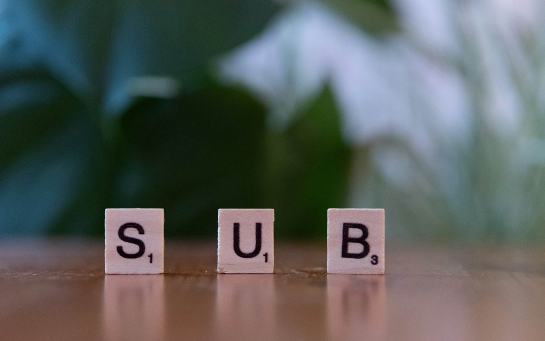 Wooden table with a block displaying the word "subscribe" in bold letters.