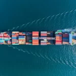 Aerial view of a cargo ship transporting colourful shipping containers across the sea
