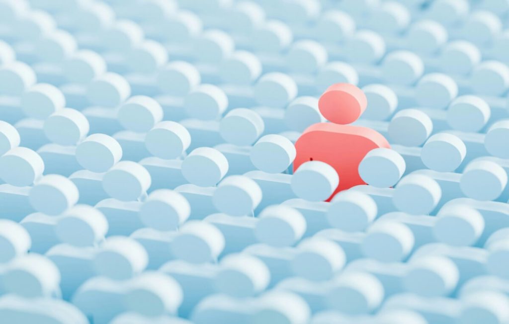 Abstract illustration of a single red figure standing out among many blue figures, representing audience diversity, localization, and personalized communication.Show more lines