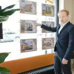 Business professional pointing at property listings in a real estate office window